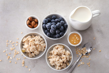 Composition with tasty oatmeal, fresh berries, milk and honey on table