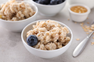 Bowl with tasty oatmeal and blueberry on table