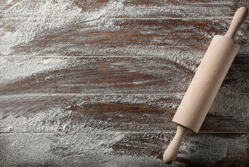 Scattered flour with rolling pin on wooden background