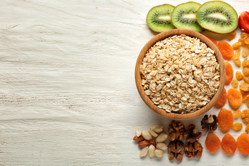 Composition with raw oatmeal, nuts and fruits on wooden background