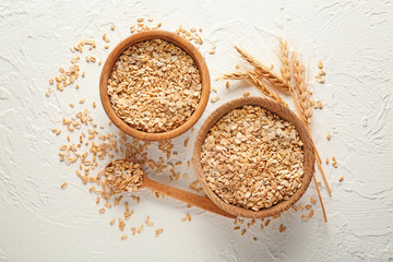 Bowls with raw oatmeal on light background