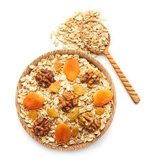 Bowl with raw oatmeal, walnut and dried fruits on white background
