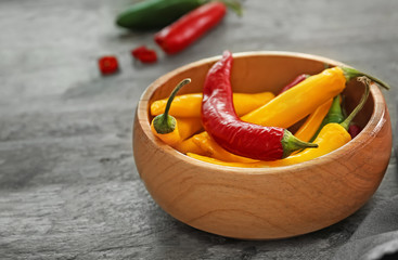 Bowl with fresh chili peppers on wooden background