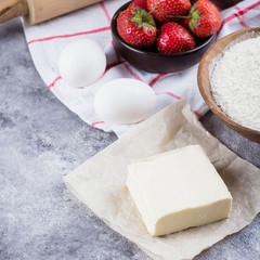 Baking ingredients for cake, pie, shortbread pastry: flour, eggs, sugar, butter, rolling pin and on gray concrete table background. Top view, copy space