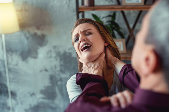 Blood on lip. Suffering woman from home abuse having blood on her lip while crazy insane man strangling her in the kitchen