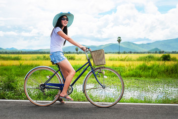 woman traveler enjoying for  view of rice field. Asian lady tourist riding a bicycle and looking...