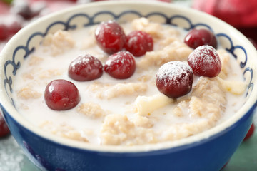 Tasty oatmeal with cherries in bowl, closeup