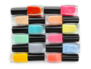 Bottles of colorful nail polish on white background, flat lay