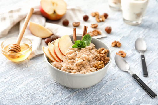 Tasty oatmeal with apple and walnut in bowl on table