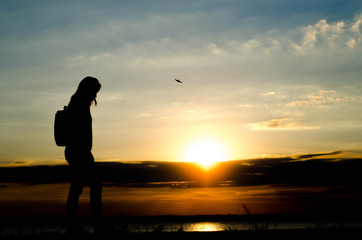 Silhouette of a woman wolking alone at the field during beautiful sunset.