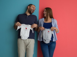 young couple holding baby bodysuits