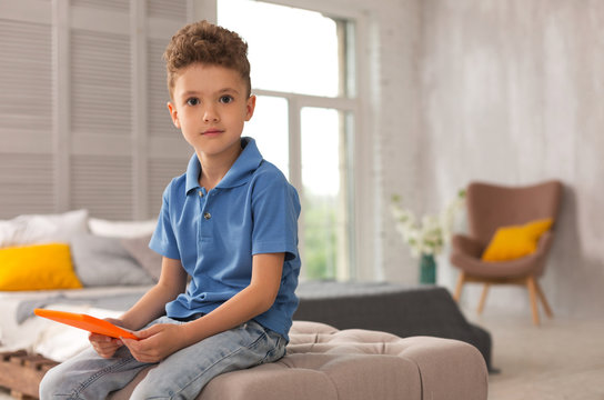 Dark-eyed Boy. Dark-eyed Pleasant Looking Cute Boy Wearing Jeans Feeling Amazing While Playing With Toys