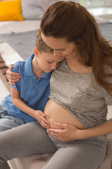 Caring mother. Caring pregnant mother feeling so memorable while hugging her little cute son...