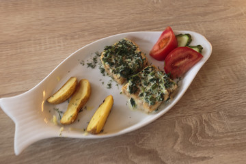 Fish dish, fried cod fillet, cod fillet fried under cheese sauce with herbs, potatoes and vegetables.