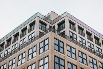 A symmetrical snapshot of a building corner with lots of windows against the sky