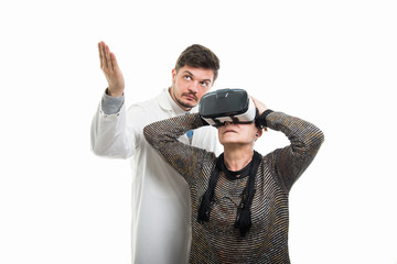 Male doctor showing to female senior patient with vr goggles