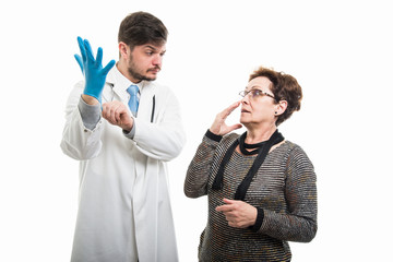 Scared female patient looking to suspicious male doctor with glove