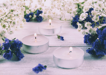 Obraz na płótnie Canvas Candles, white and blue flowers on a white background