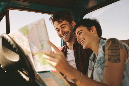 Young travellers on a road trip looking at map