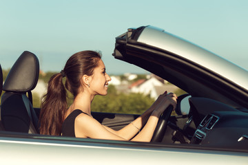 young girl driving cabrio car, on sunset light