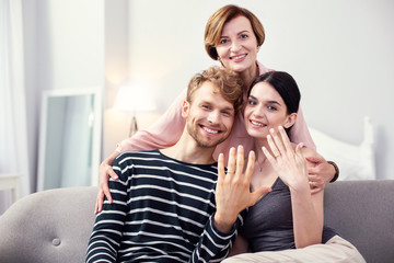 Happy family. Nice aged woman standing behind the couple while hugging them