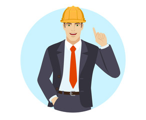 Businessman in construction helmet with hand in pocket pointing up