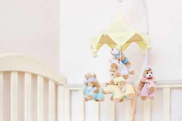 Close-up baby crib with musical animal mobile at nursery room. Hanged developing toy with plush fluffy animals. Happy parenting and childhood, expectation delivery of a child concept