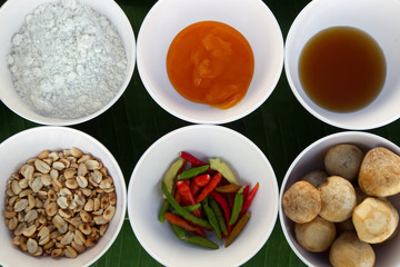 Top view mix thai spices and herbs  on white plate .banana leaf background with copy space for design vegetable, healthy lifestyle, spices, herbs or foods content