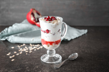 Tasty oatmeal dessert with fresh pomegranate seeds in glass cup on table