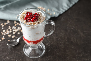 Tasty oatmeal dessert with fresh pomegranate seeds in glass cup on table