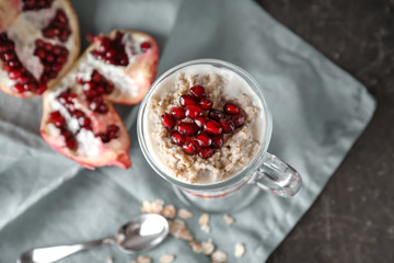 Tasty oatmeal dessert with fresh pomegranate seeds in glass cup on table