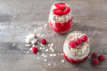 Fototapeta na wymiar Delicious oatmeal desserts with fresh raspberries in glasses on wooden table
