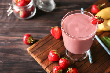 Glass with tasty strawberry smoothie on wooden table
