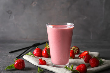 Glass with tasty strawberry smoothie on grey table