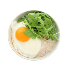 Bowl with tasty oatmeal, fried egg and arugula on white background