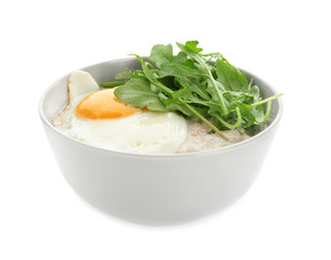 Bowl with tasty oatmeal, fried egg and arugula on white background