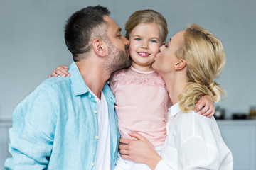 happy parents kissing adorable little daughter at home