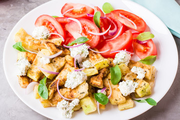 Fried zucchini with feta cheese, tomatoes, herbs and onions on a plate