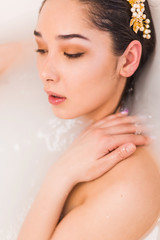 Naklejka premium Closeup portrait of a young woman relaxing in the milk. Girl profile with closed eyes in bath