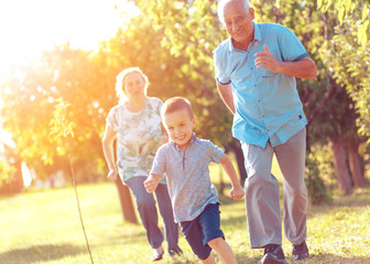 Grandparents with grandson enjoying time together in park. - obrazy, fototapety, plakaty