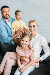 happy family with two adorable kids smiling at camera at home
