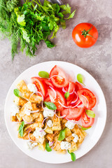 Fried zucchini with feta cheese, tomatoes, herbs and onions on a plate. Delicious appetizer ready to eat. Top view