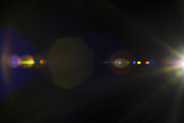 Solar camera lens flare light create hexagon of objective iris shapes of different colors depending on used antireflection coating of each lens surface on dark black background