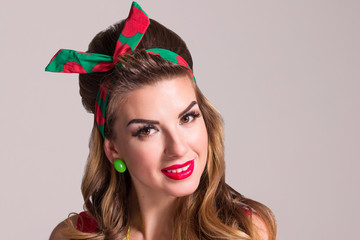 Young woman with hairdo and make up poses in studio, pin up style, close up portrait