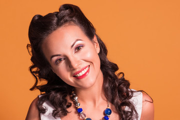 Beautiful brunette with hairdo and make up smiles in studio, pin up style, close up portrait