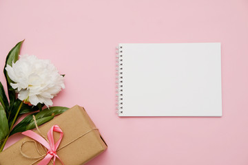 Composition with flowers, gift and notebook on pink background. Mock up for your design. Flat lay.