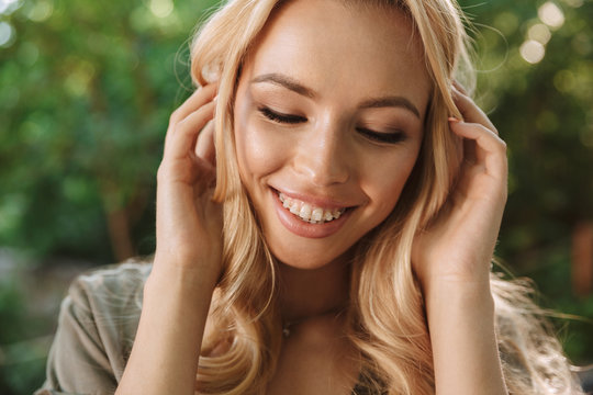 Picture of Smiling sensual blonde woman in dress touching hair