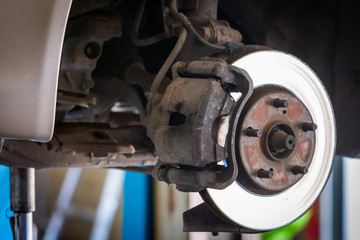 Front disc brake on car in process of service. The rim is removed showing the front rotor and caliper