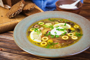 Russian soup solyanka with sour cream on wooden background