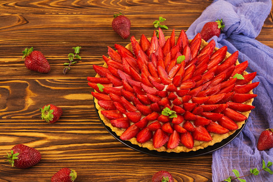 Delicious tart with strawberry on wooden background